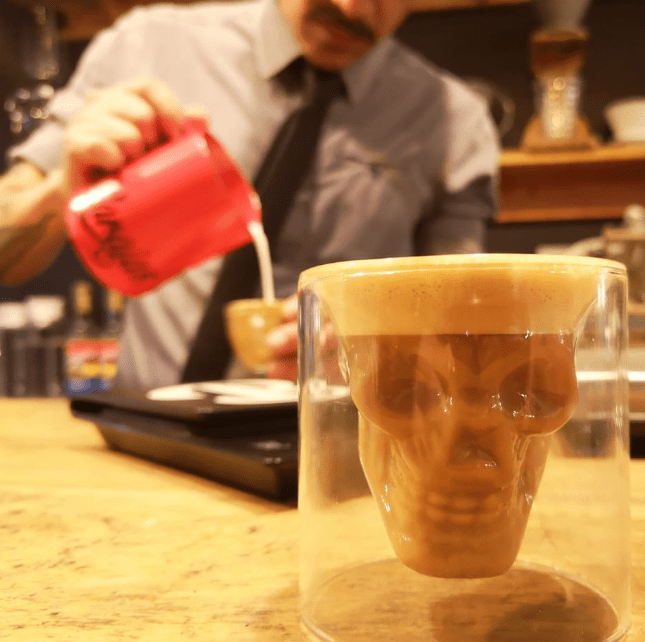 a person sitting at a table with a cup of coffee